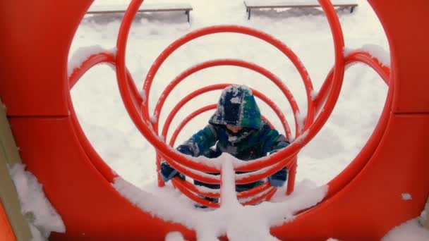 Chłopak gra na placu zabaw w zimie. — Wideo stockowe