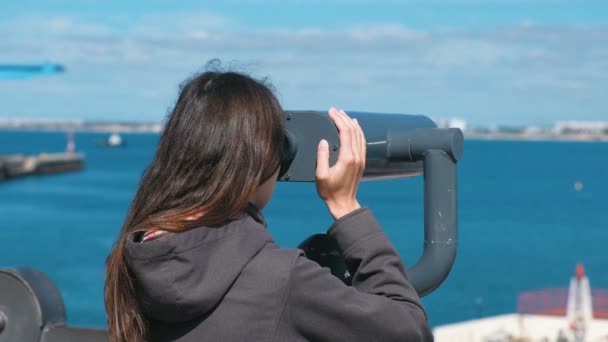Donna irriconoscibile bruna guarda attraverso il binocolo verso il mare . — Video Stock