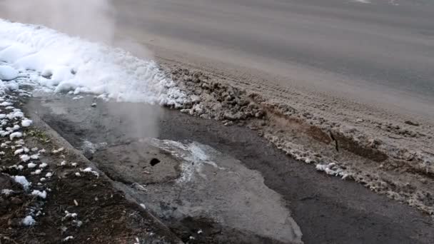 Steam is from sanitary sewer cover in snow on the roadside. Side view. — Stock Video