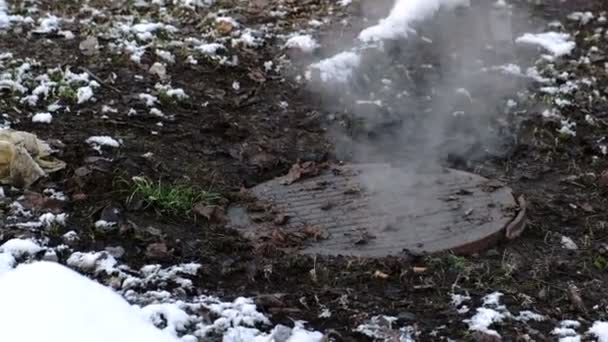 La vapeur provient de la couverture d'égout sanitaire dans la neige, accident. De la neige fondue. Vue rapprochée . — Video