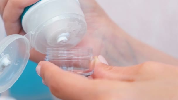 Womens handen zet een gezicht scrub in een kleine pot. De reeks van de weg van cosmetica. Close-up jar. — Stockvideo