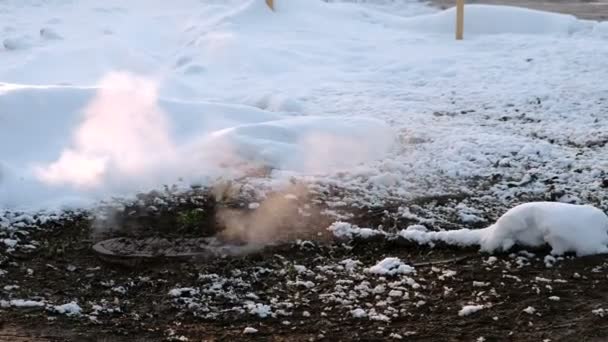 La vapeur provient de la couverture d'égout sanitaire dans la neige, accident. Mouvement de caméra . — Video