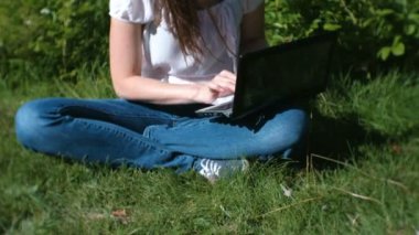 Yaz aylarında parkta oturan laptop yazmaya çalışan genç kadın. Eller yakın çekim.