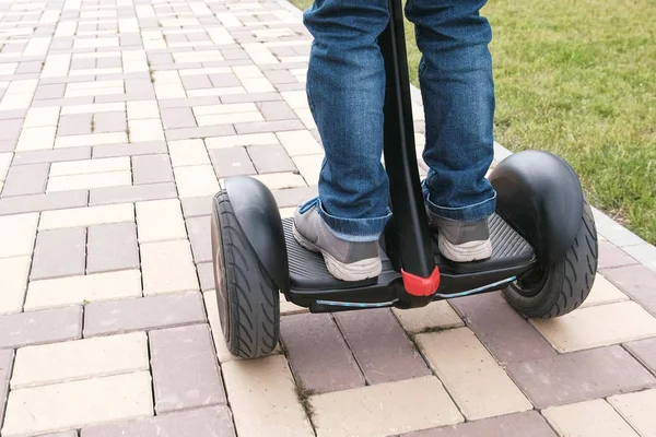 Un chico irreconocible está rodando en un scooter giratorio cerca de la casa. Vista trasera. Primer plano de las piernas . —  Fotos de Stock