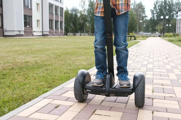 Un chico irreconocible está rodando en un scooter giratorio cerca de la casa. Primer plano de las piernas . —  Fotos de Stock