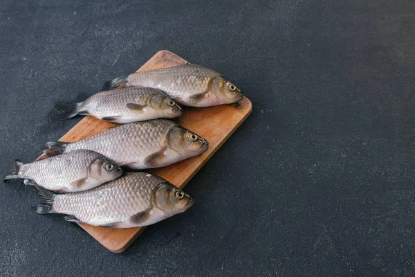 A cozinhar peixe. Pequenas carpas frescas na mesa em uma tábua de madeira close-up . — Fotografia de Stock