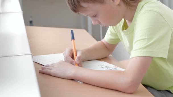 Jongen van de school kind leert om brieven zitten door de tabel te schrijven. Huiswerk. — Stockvideo