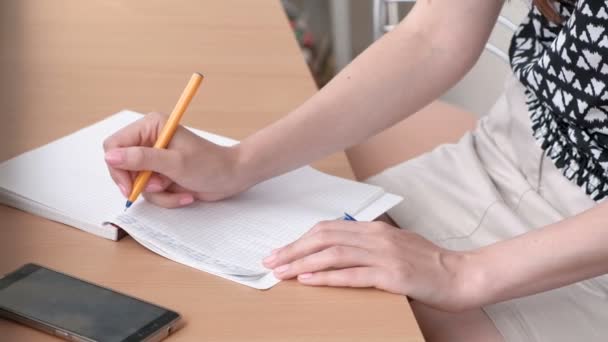 女性は自宅のバルコニーでノート sitiing で何かを書いています。梨花のクローズ アップの手. — ストック動画