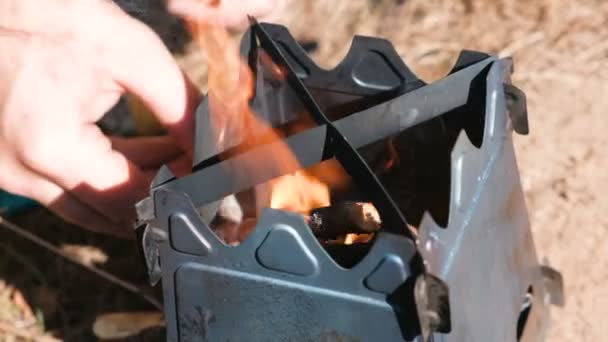 El hombre inflama la estufa de horno de campamento de metal en los bosques al aire libre. Manos de hombre de cerca. Vista superior . — Vídeo de stock