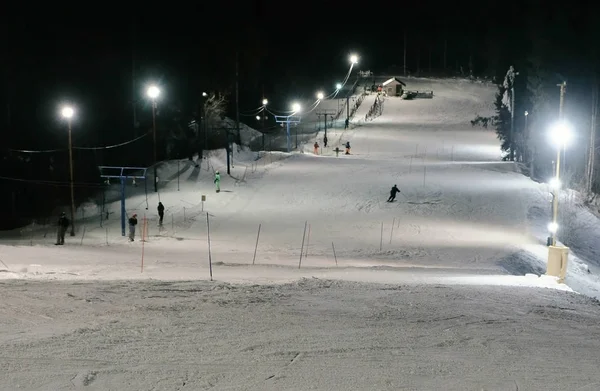 Mann fährt abends auf einem Skihang neben dem Lift den Berg hinunter. — Stockfoto