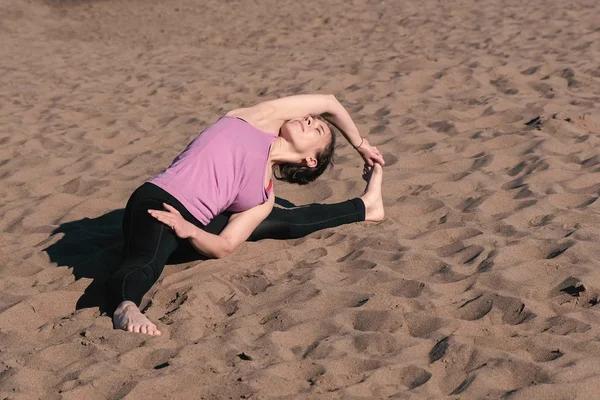 Mujer estirando yoga en la playa de la ciudad. Sirsasana, Supta upavistha konasana pose . —  Fotos de Stock