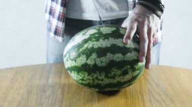 Adam keser bir karpuz iki yarısı mutfak masasının üzerinde. Eller yakın çekim.