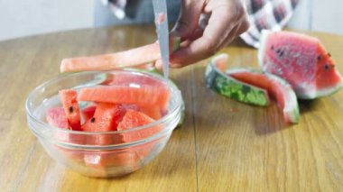 Adam bir karpuz kabuğu dan eti keser ve bir kase içinde koyar.
