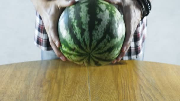 Man puts a watermelon on the kitchen table. Close-up hands. — Stock Video