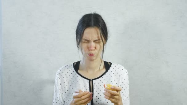 Emoties van de zure op het gezicht van de meisjes. Brunette vrouw eten zure tangerine en huiverend. — Stockvideo