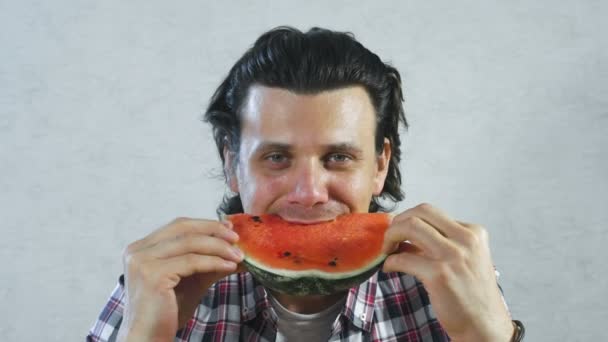 Brunet man is eating juicy watermelon on white background. — Stock Video