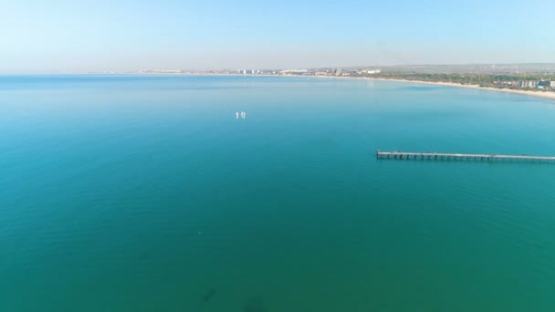 Vista a volo d'uccello sulla spiaggia sabbiosa, sul mare, sulla città balneare e sul molo . — Video Stock