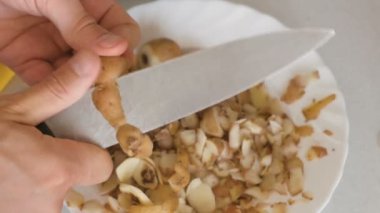 Eller mans mutfak bıçağıyla patates soyma.
