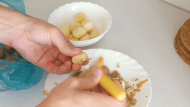 Mans rukou je loupání brambor s žlutým škrabka. — Stock video