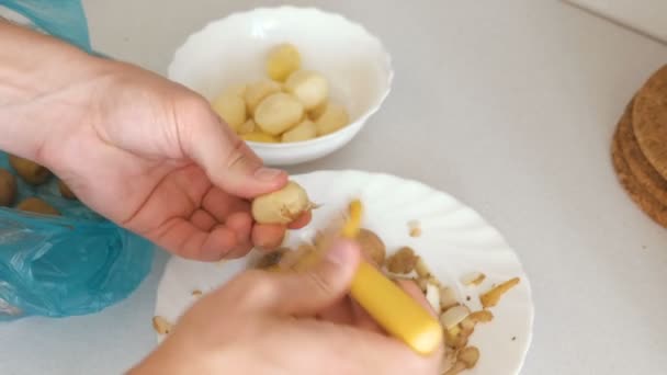 Mans handen is peeling aardappel met gele dunschiller. — Stockvideo