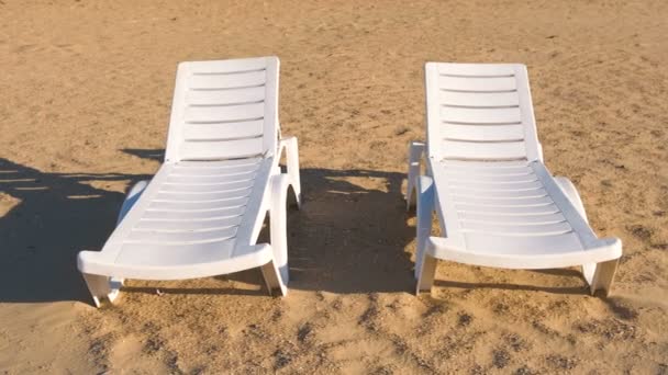 Zwei Sonnenliegen am Sandstrand aus nächster Nähe. — Stockvideo