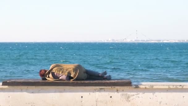 Femme sans abri dormant sur un banc sur le front de mer . — Video