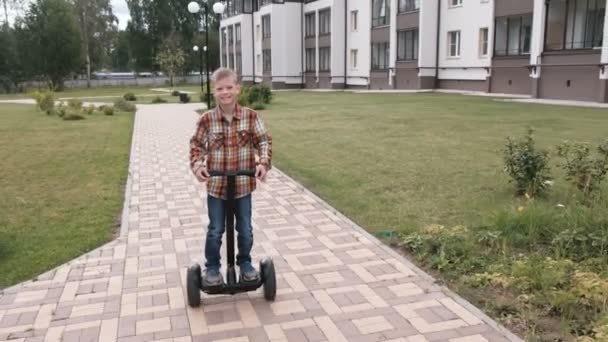 Jongen rolt op gyro scooter in de buurt van het huis. — Stockvideo