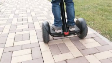 Tanınmayan çocuk evinizin yakınında gyro scooter üzerinde inişli çıkışlı olduğunu. Arkadan görünüm. Bacaklar yakın çekim.