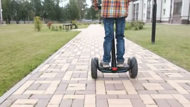 Onherkenbaar jongen ontwikkelt op gyro scooter in de buurt van het huis. Achteraanzicht. — Stockvideo
