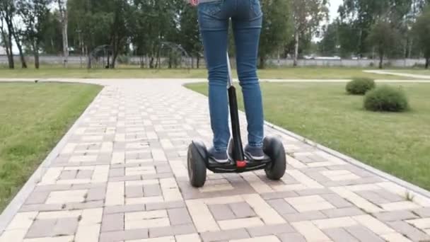 Morena mujer está rodando en scooter giroscopio cerca de la casa, vista trasera . — Vídeos de Stock