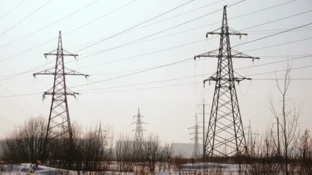 Torres de alta tensión, línea de transmisión en el fondo de la ciudad de invierno. Cámara moviéndose de abajo hacia arriba . — Vídeos de Stock