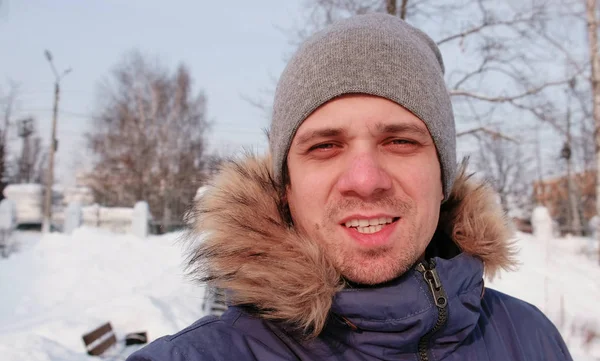 Portret van de jonge man winter in grijze afdekkap en blauw donsjack camera kijken. — Stockfoto