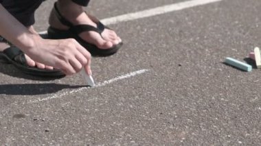 Kadın bir kare beyaz tebeşir ile asfalt üzerinde çizer. Yakın çekim yakışıklı.