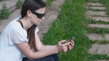 Kadın parkta oturan telefonunda bir mesaj türleri.