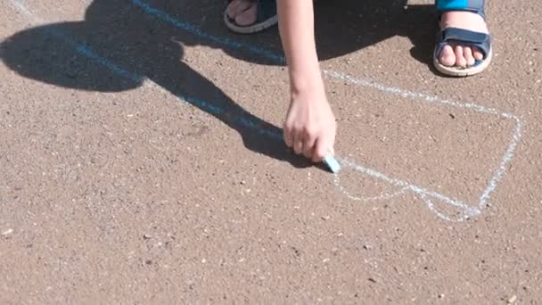 Junge zeichnet mit blauer Kreide auf den Asphalt. Hände aus nächster Nähe. — Stockvideo