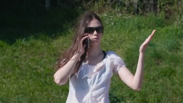 Jeune femme parlant téléphone mobile marche dans le parc .