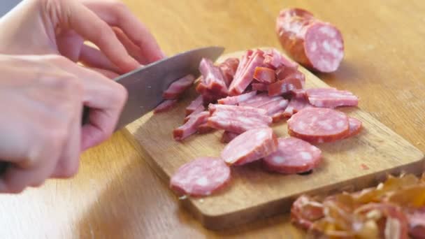 Close-up view of womans hands cutting the smoked sausage for slices and pieces. — Stock Video