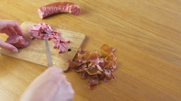 Las manos de las mujeres están cortando la salchicha ahumada para rebanadas y piezas para pizza . — Vídeos de Stock