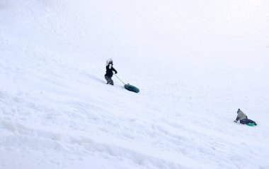 Kış parkta boru içinde karlı dağlardan çocuk binmek.