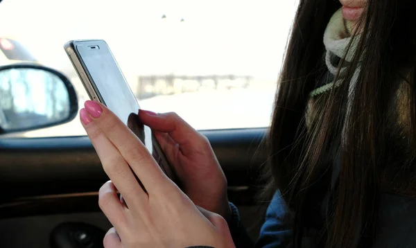 Primeros planos de las mujeres manos charlando su teléfono móvil sentado en el coche. Vista lateral . — Foto de Stock