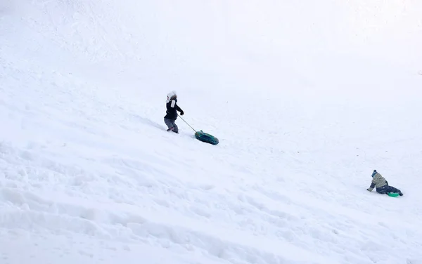 Kinder fahren aus den verschneiten Bergen im Tubing im Winterpark. — Stockfoto