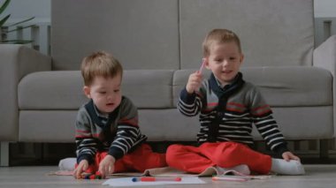 İki ikiz kardeşler küçük çocuklar birlikte katta oturan işaretleri çizmek.