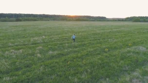 Çocuk sahada günbatımı üzerinde çalışıyor. Arkadan görünüm. — Stok video