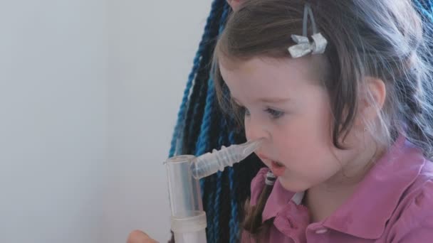Kleines süßes Mädchen, das mit seiner Mutter durch die Atemmaske inhaliert. Vernebler und Inhalator für die Behandlung verwenden. — Stockvideo