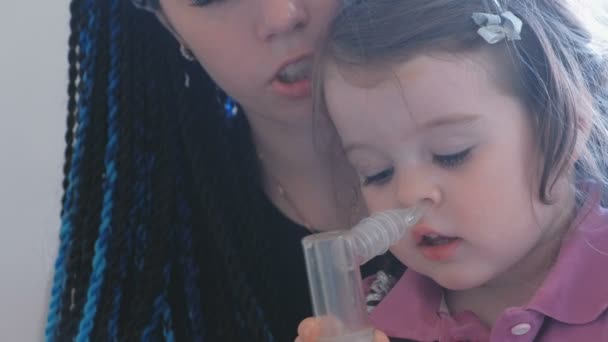 Pequena menina bonito inalando através de máscara inalador com sua mãe. Use nebulizador e inalador para o tratamento . — Vídeo de Stock