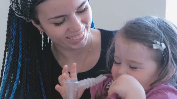 Küçük şirin kız annesiyle inhaler maskesi teneffüs edilmesi. Nebulizatör ve astım tedavisi için kullanın. — Stok video