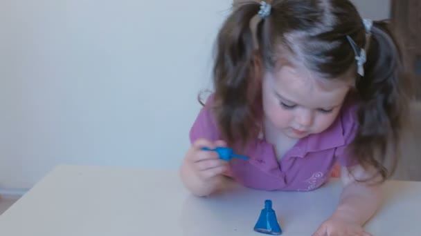 Schattig meisje schildert haar nagels met blauw lak. — Stockvideo