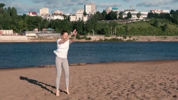 Žena, která dělá sportovní cvičení na břehu řeky ve městě. Skákat ze sedu. — Stock video