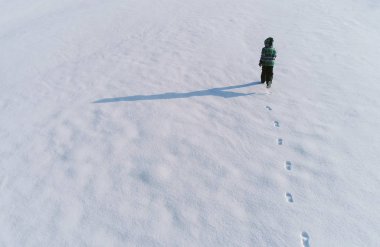 Çocuk bir karla kaplı alan üzerinde çalışıyor. Arkadan görünüm. Hava foto.