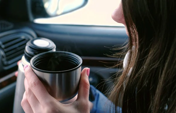 Vista de perto da mulher irreconhecível bebendo um chá quente em uma xícara de garrafa térmica sentada no carro no inverno . — Fotografia de Stock